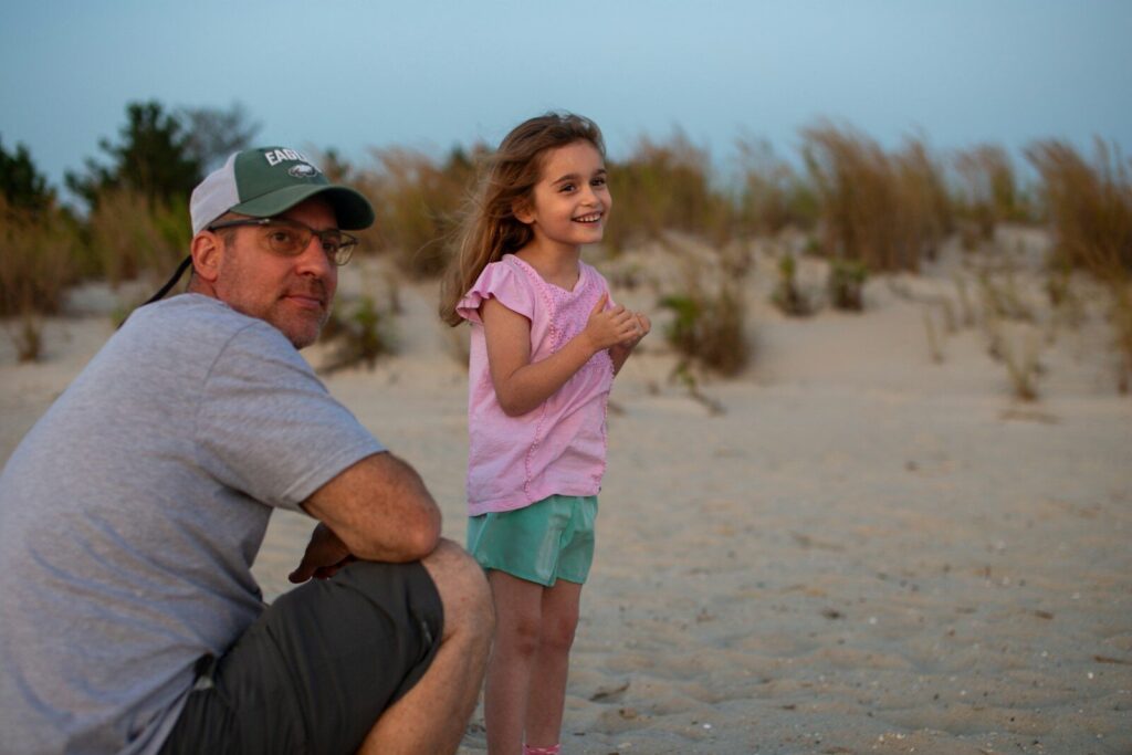 Man and girl on a sandy beach with grass
